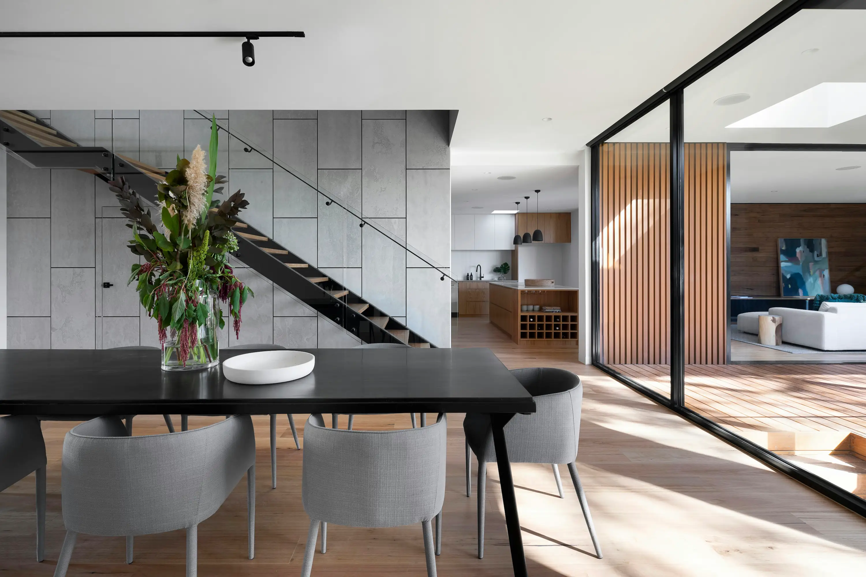 Modern home interior with an open kitchen, staircase, dining area, and living room